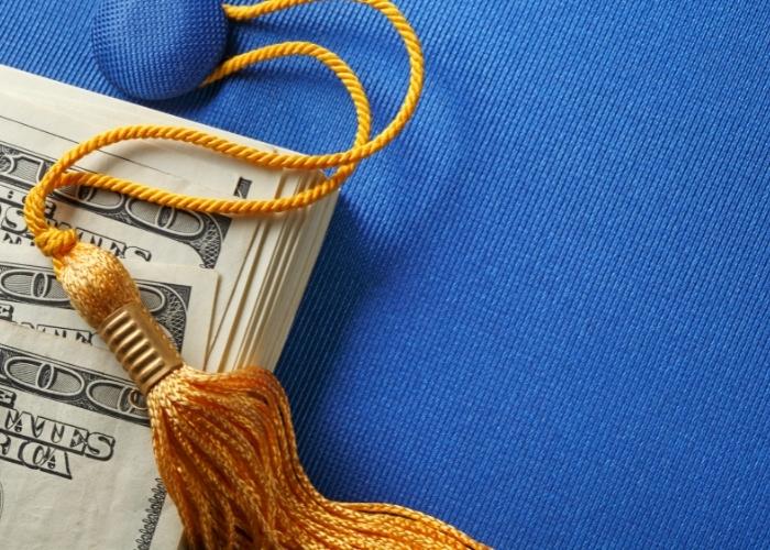 graduation cap with tassel and wrapped 100 dollar bills