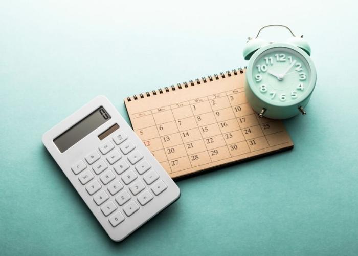 calculator calendar and alarm clock on green background