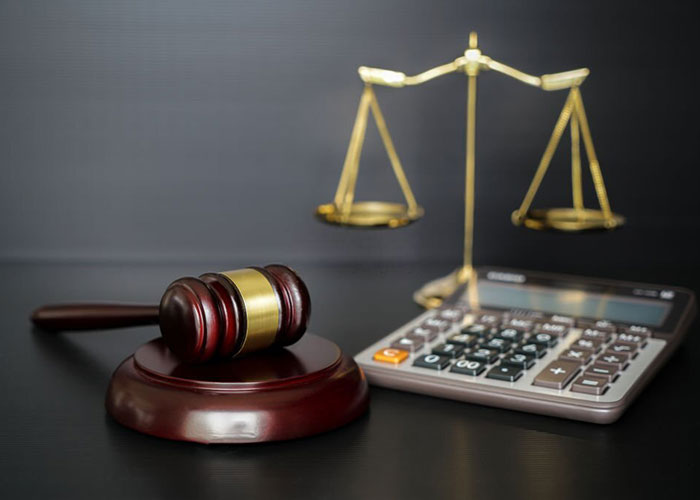 judge gavel calculator and gold scale on dark background